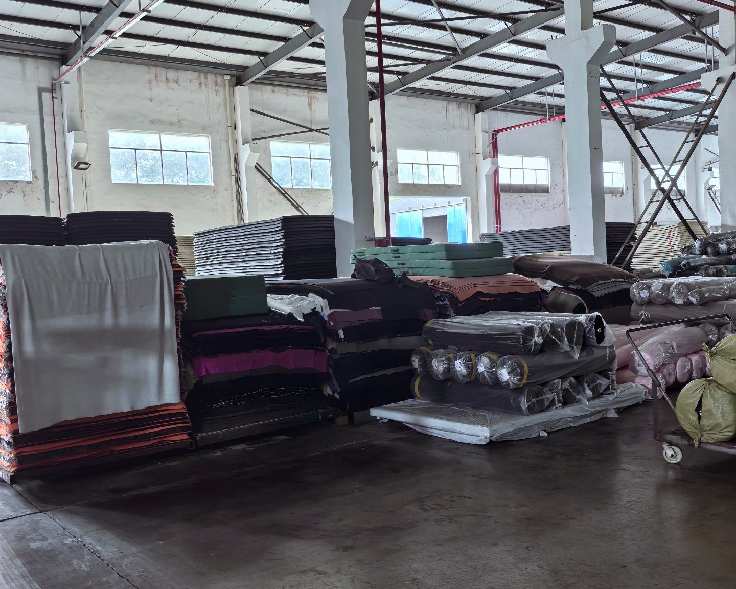 Backing and laminated fabrics in assorted colours stacked in the material store