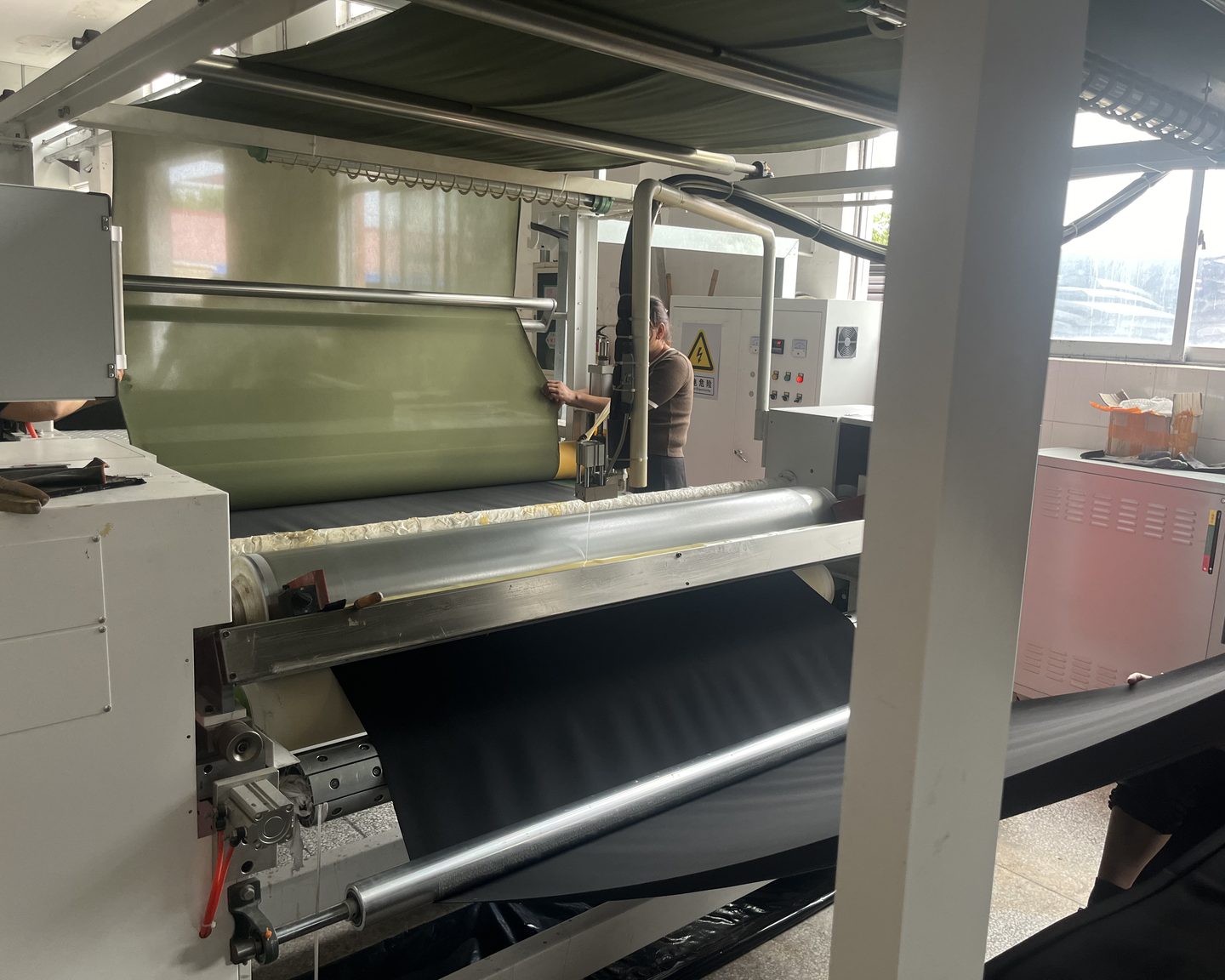 Operator feeding knit backing into the laminating machine as the neoprene core is bonded to it