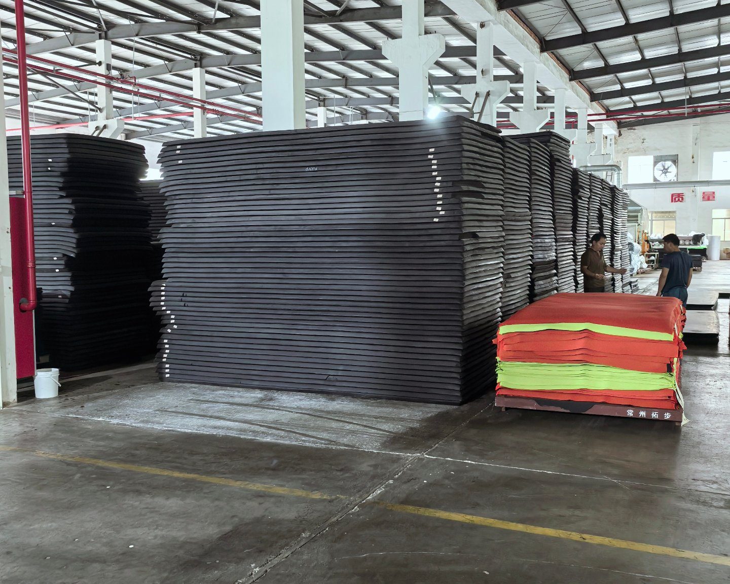 Black SCR foam sheets stacked in the partner plant store, with high-visibility roll goods alongside